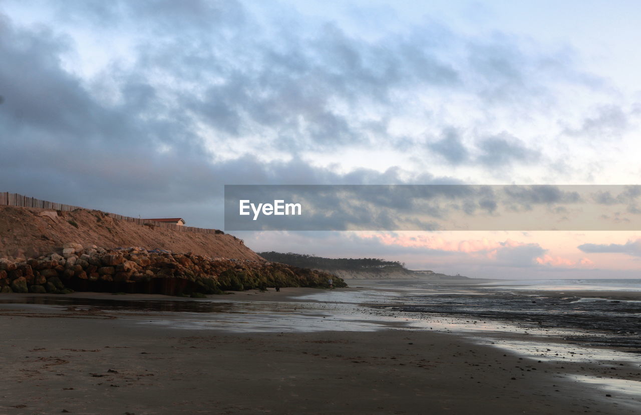 Scenic view of beach against cloudy sky