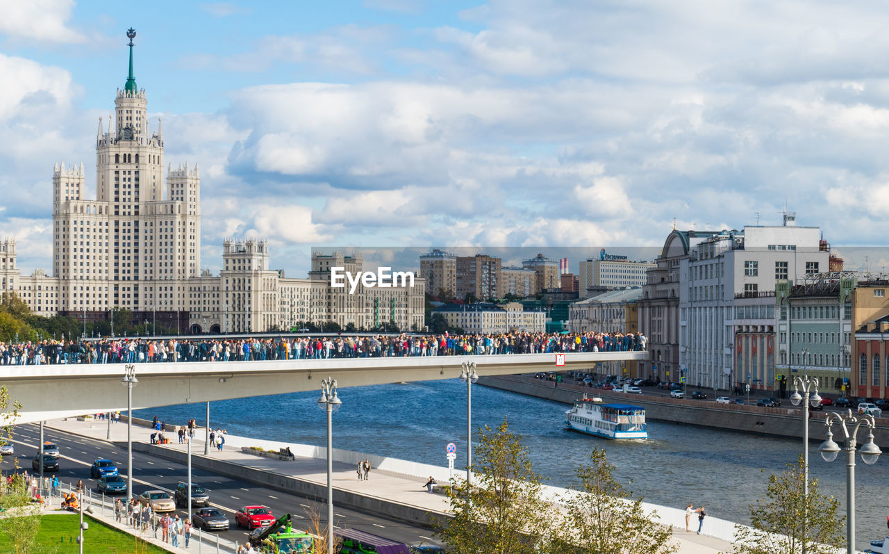 City by river and buildings against sky