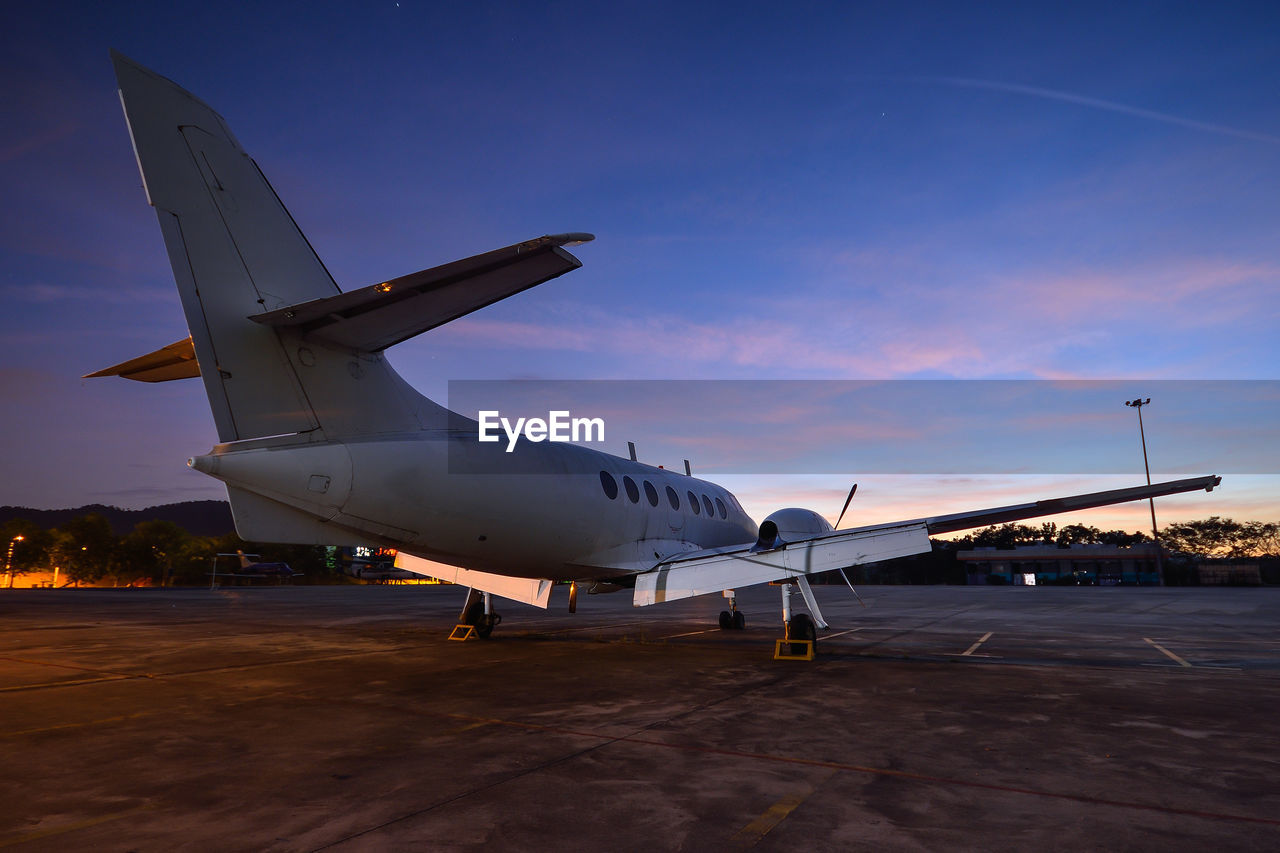 AIRPLANE AT AIRPORT RUNWAY AGAINST SKY