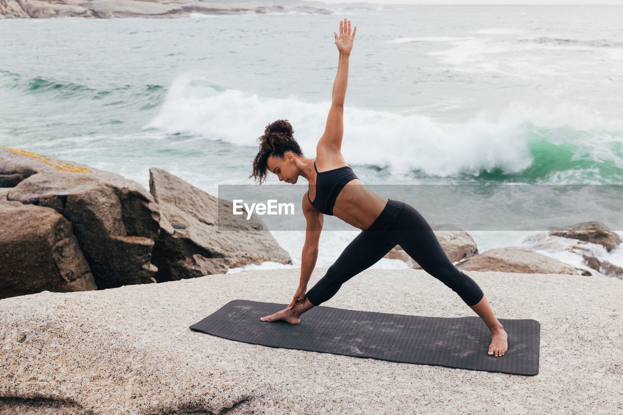 rear view of young woman doing yoga on beach