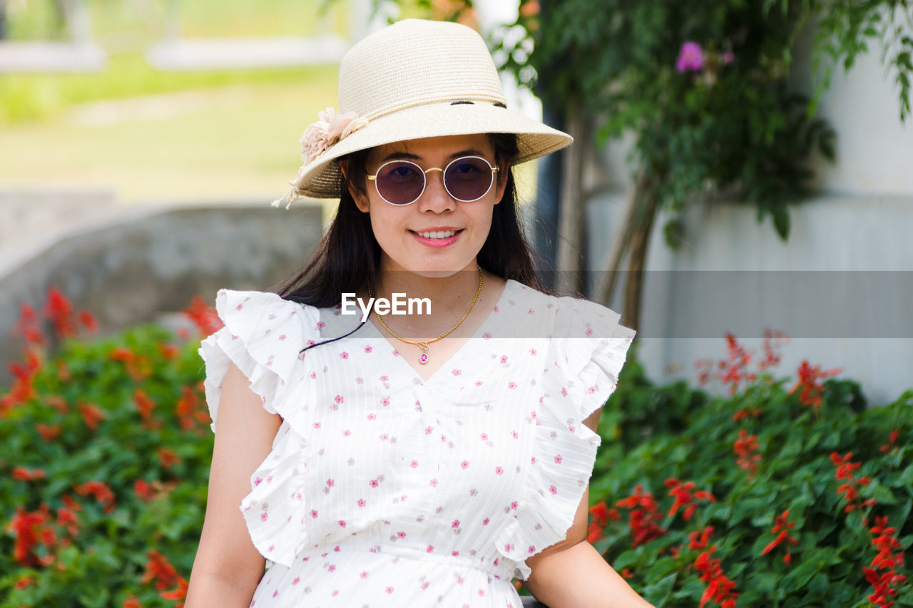 Portrait of smiling young woman wearing sunglasses in park
