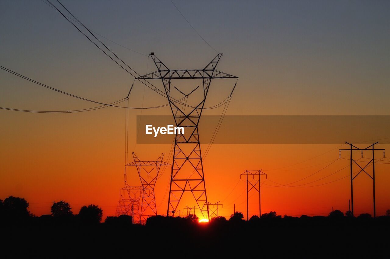 Low angle view of silhouette electricity pylon against sky during sunset