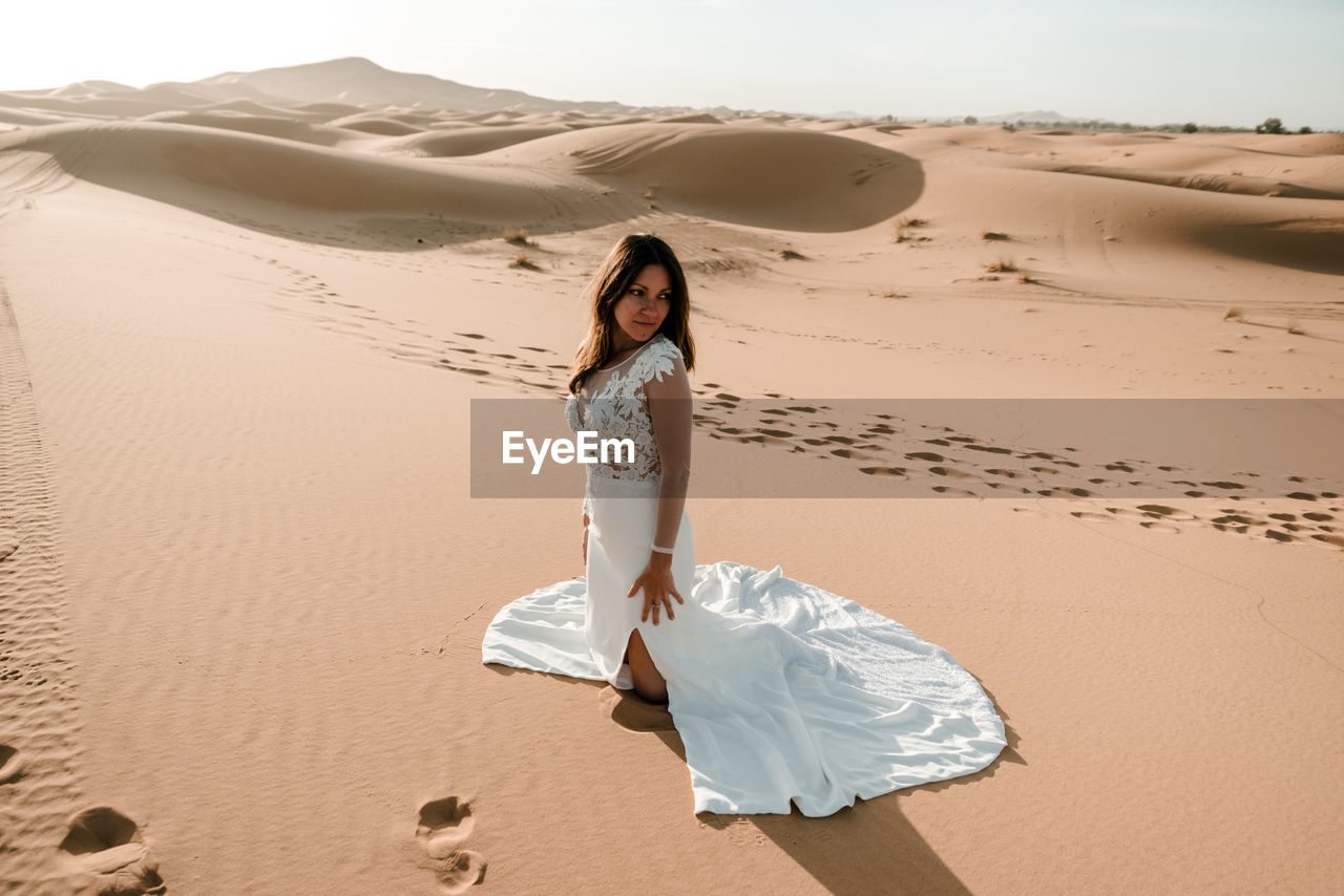 WOMAN STANDING ON SAND DUNE