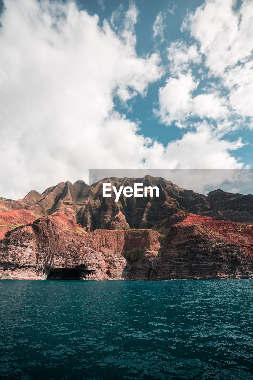 Scenic view of rock mountain by sea against sky