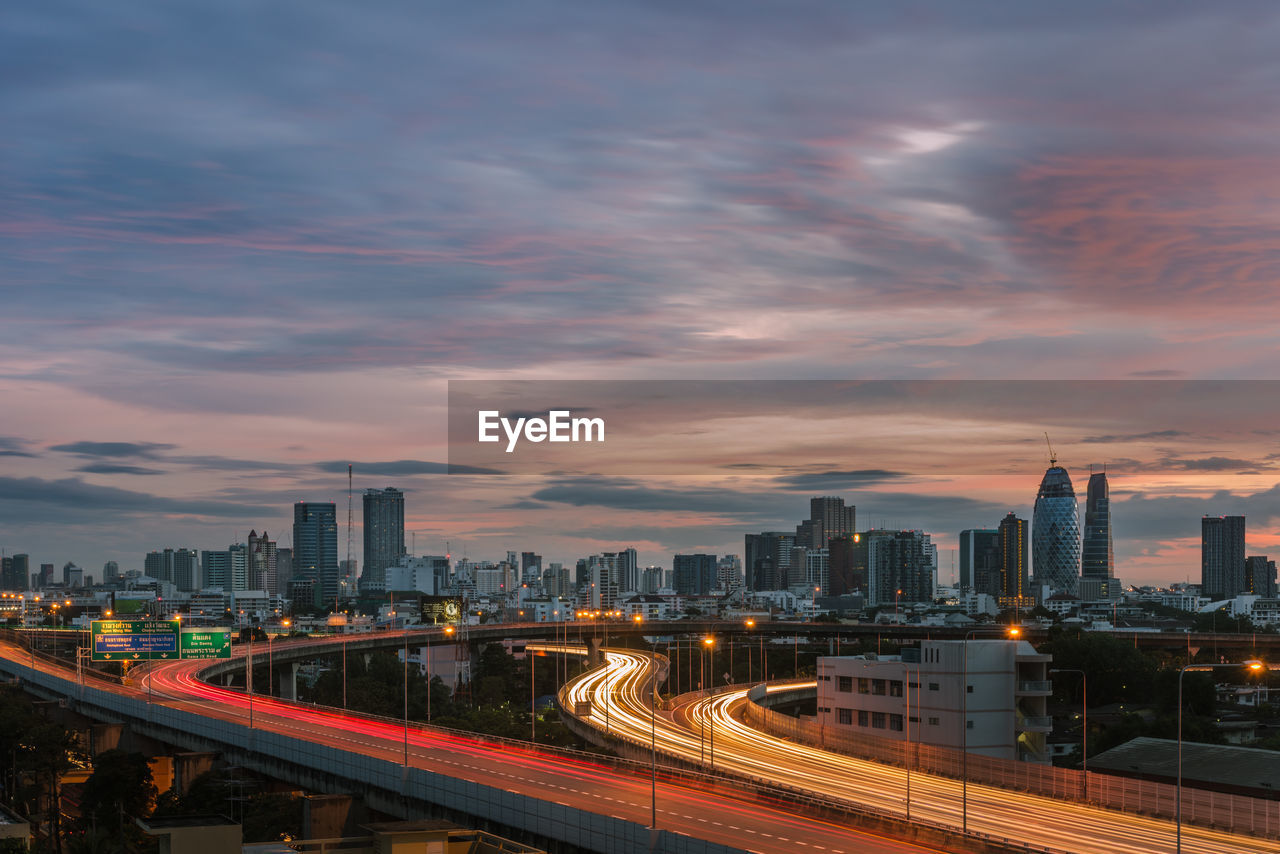 High angle view of light trails on bridge against sky during sunset in city