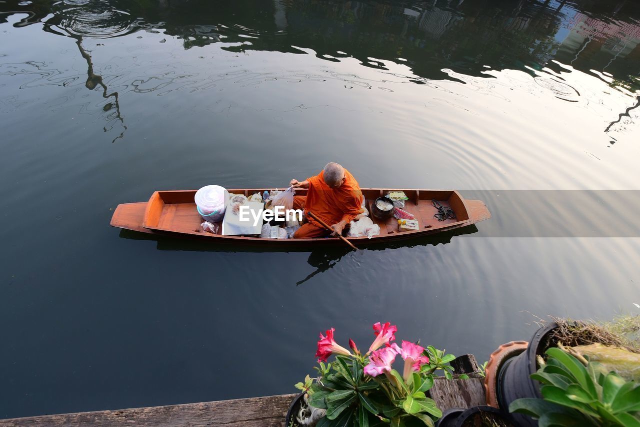 HIGH ANGLE VIEW OF PEOPLE SITTING ON LAKE AGAINST SKY