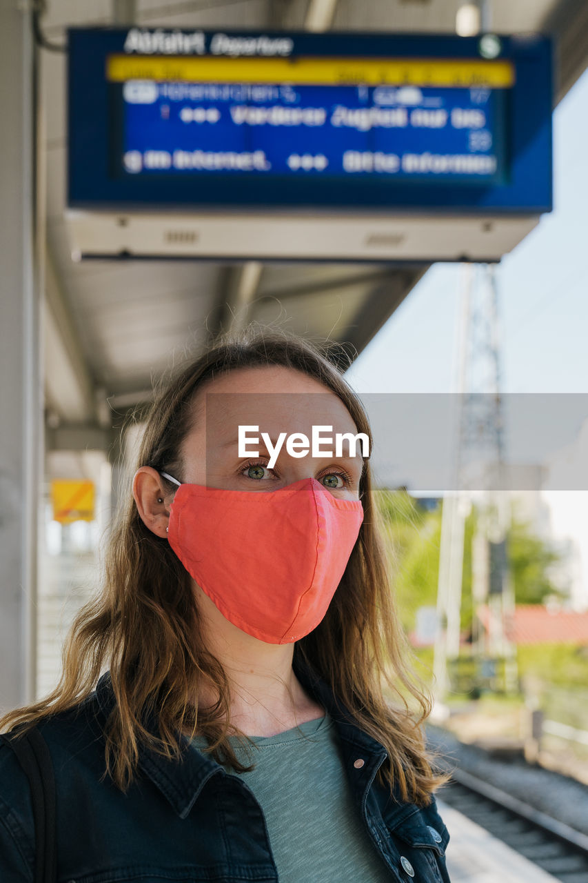 Close-up of woman wearing mask standing at railroad station