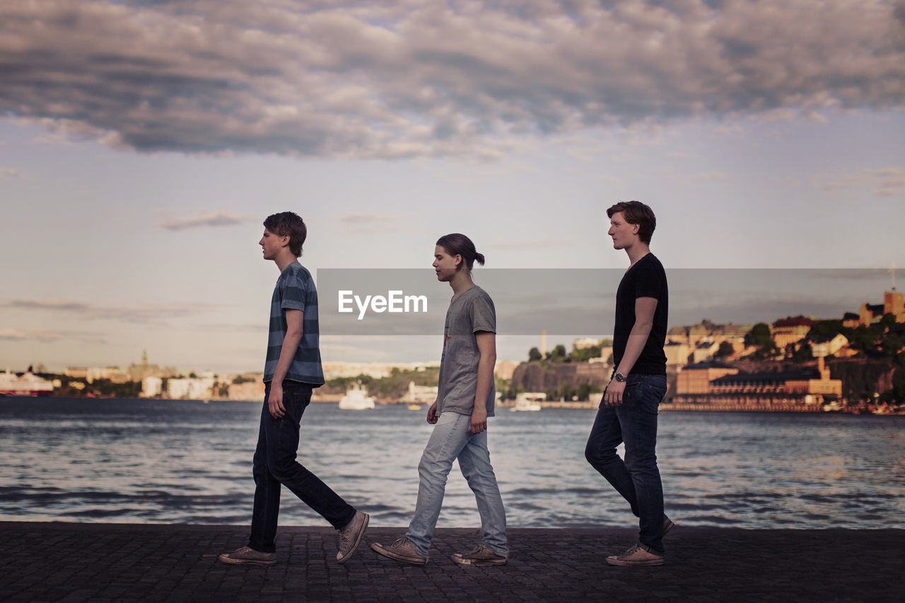 Profile shot of young men walking in a row on pier