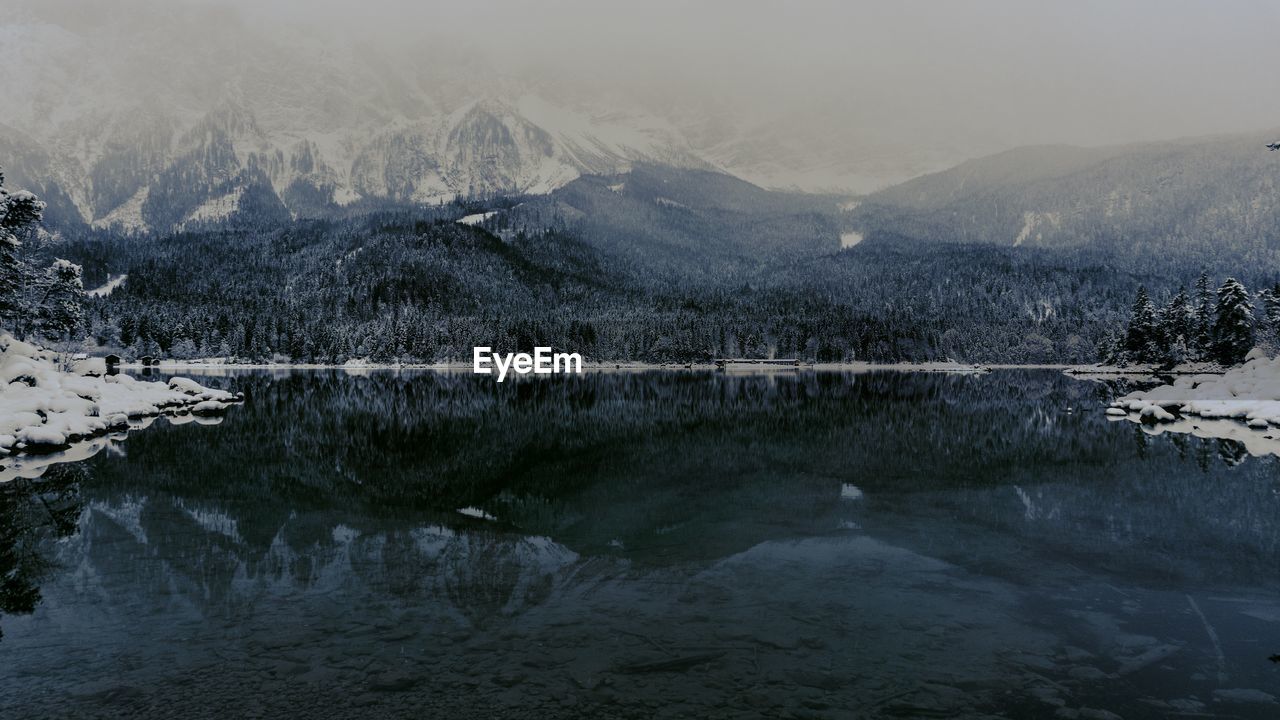 Scenic view of lake by snowcapped mountains against sky