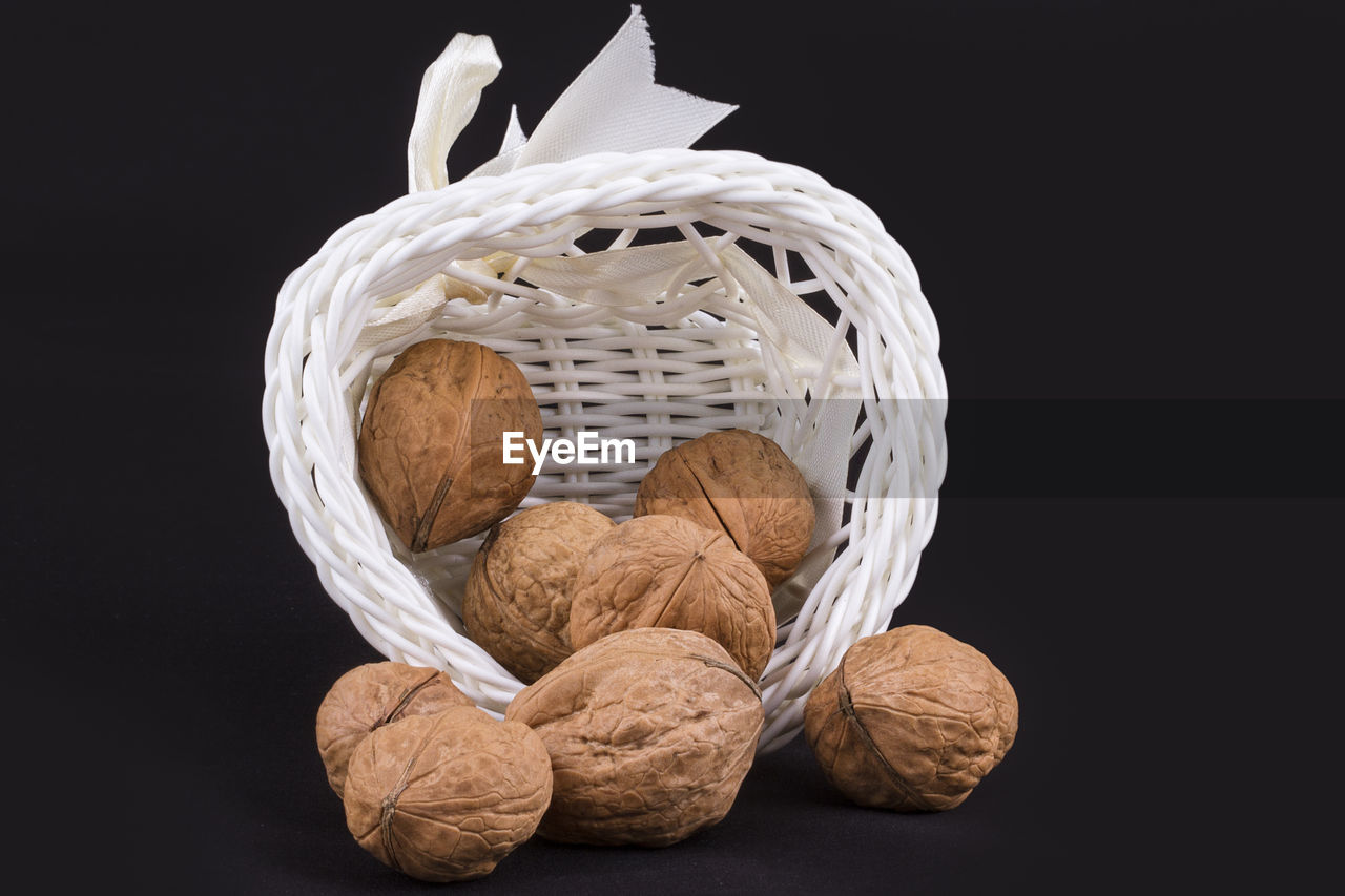 Close-up of walnuts in basket against black background