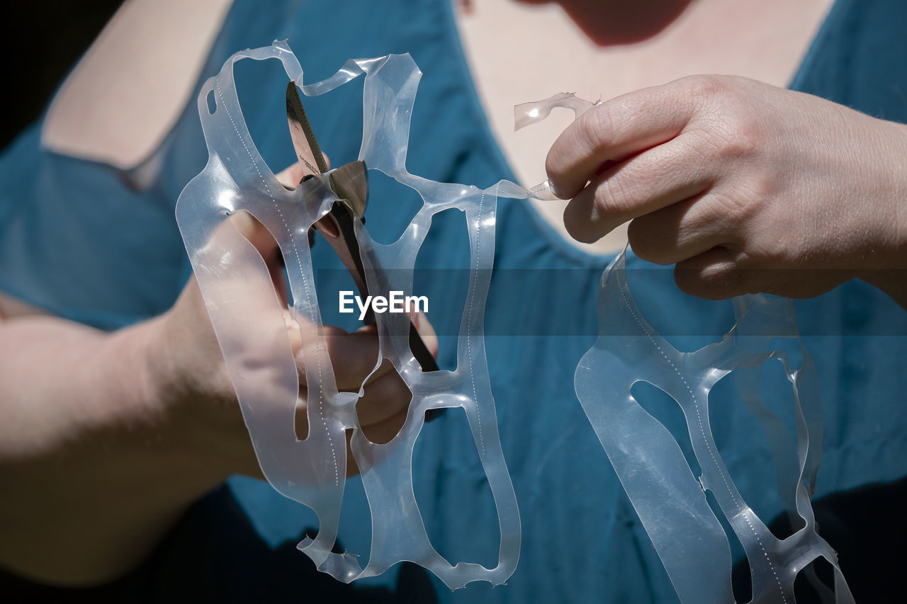 Midsection of woman cutting plastic with scissors