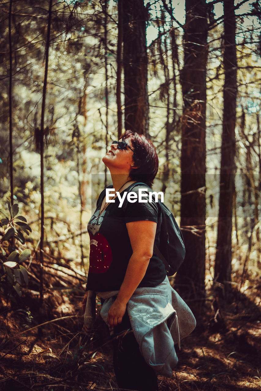 Side view of woman standing in forest