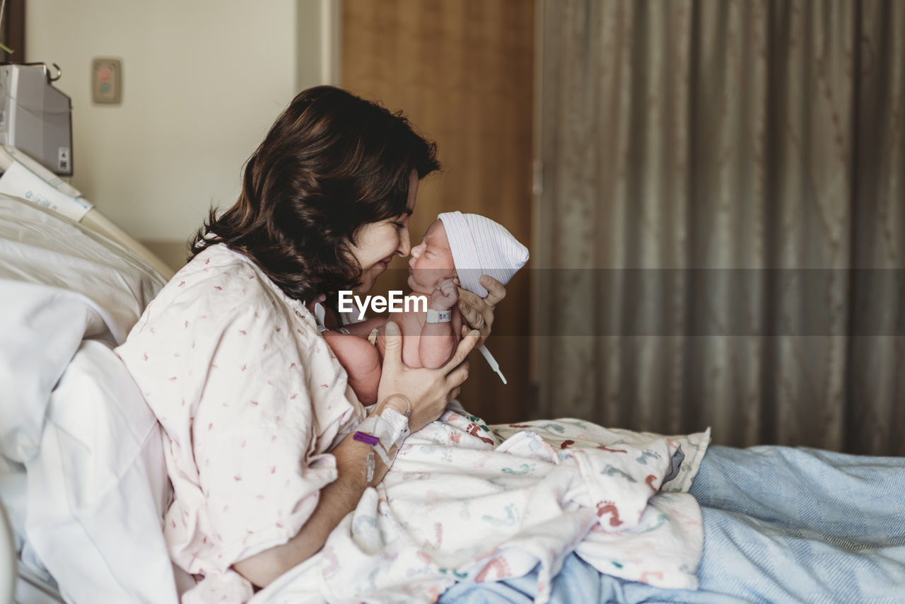 Side view of mother and newborn son touching noses in hospital