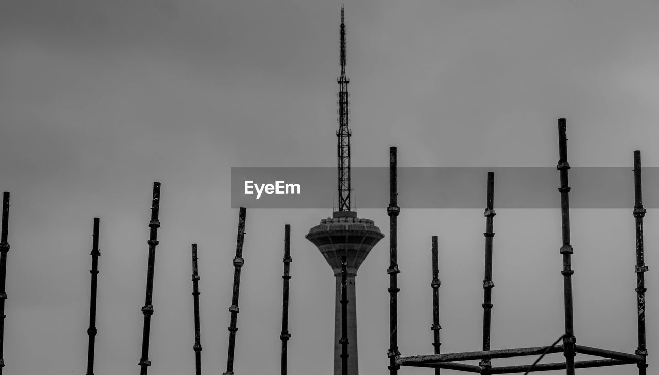 LOW ANGLE VIEW OF COMMUNICATIONS TOWER AND BUILDINGS AGAINST SKY