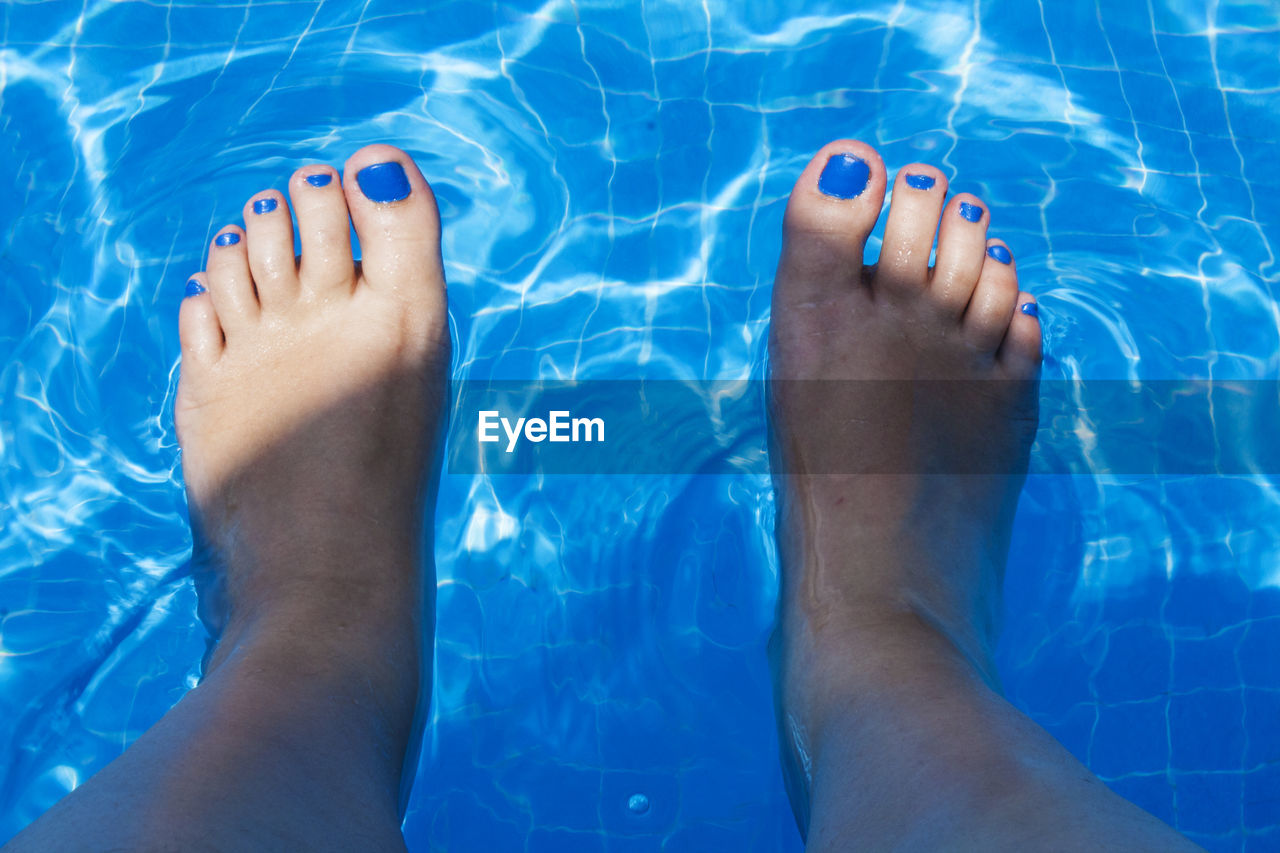 Low section of bare feet in swimming pool
