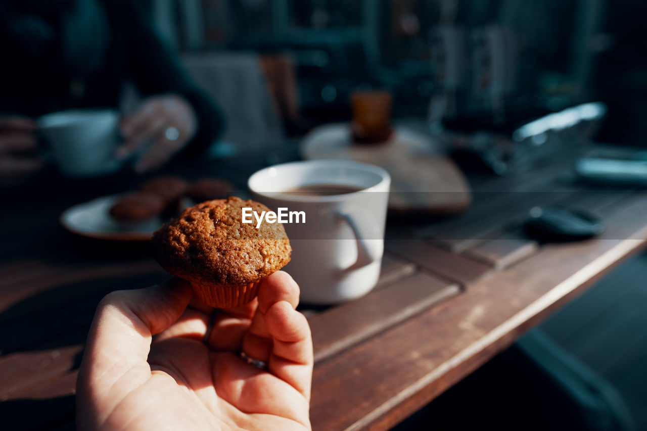 Close-up of hand holding cake on table