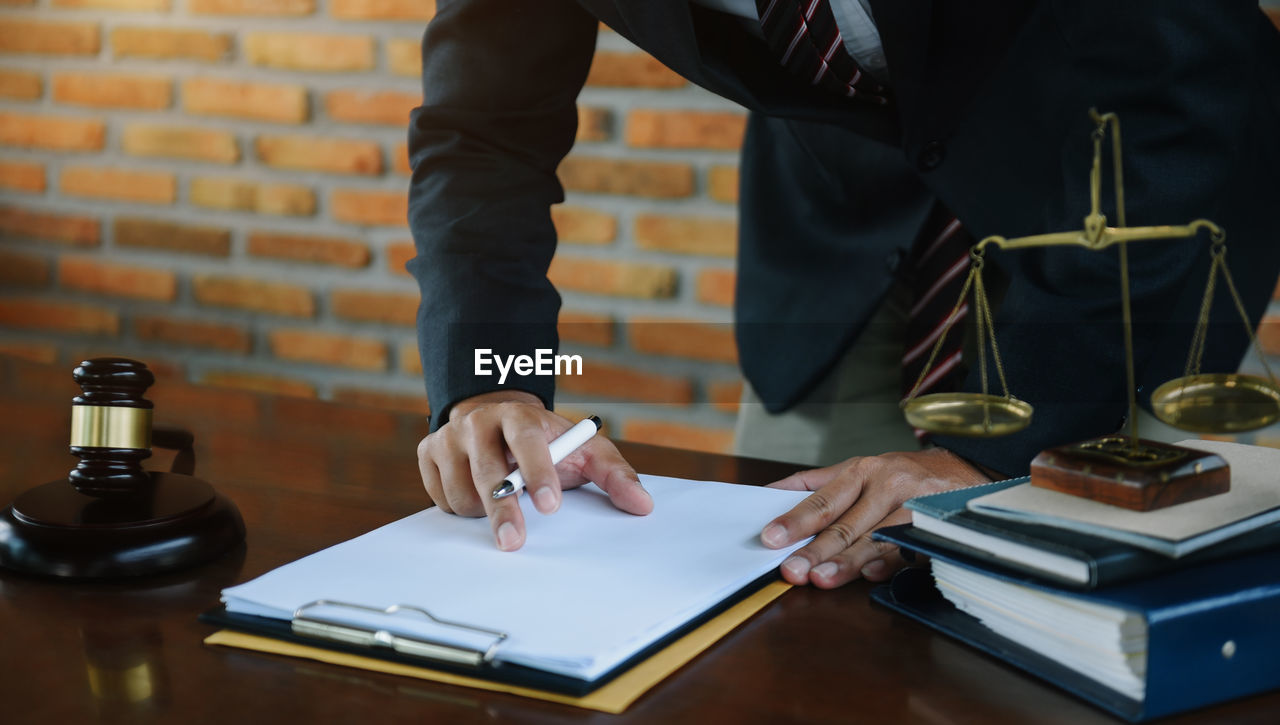 midsection of lawyer reading book at table