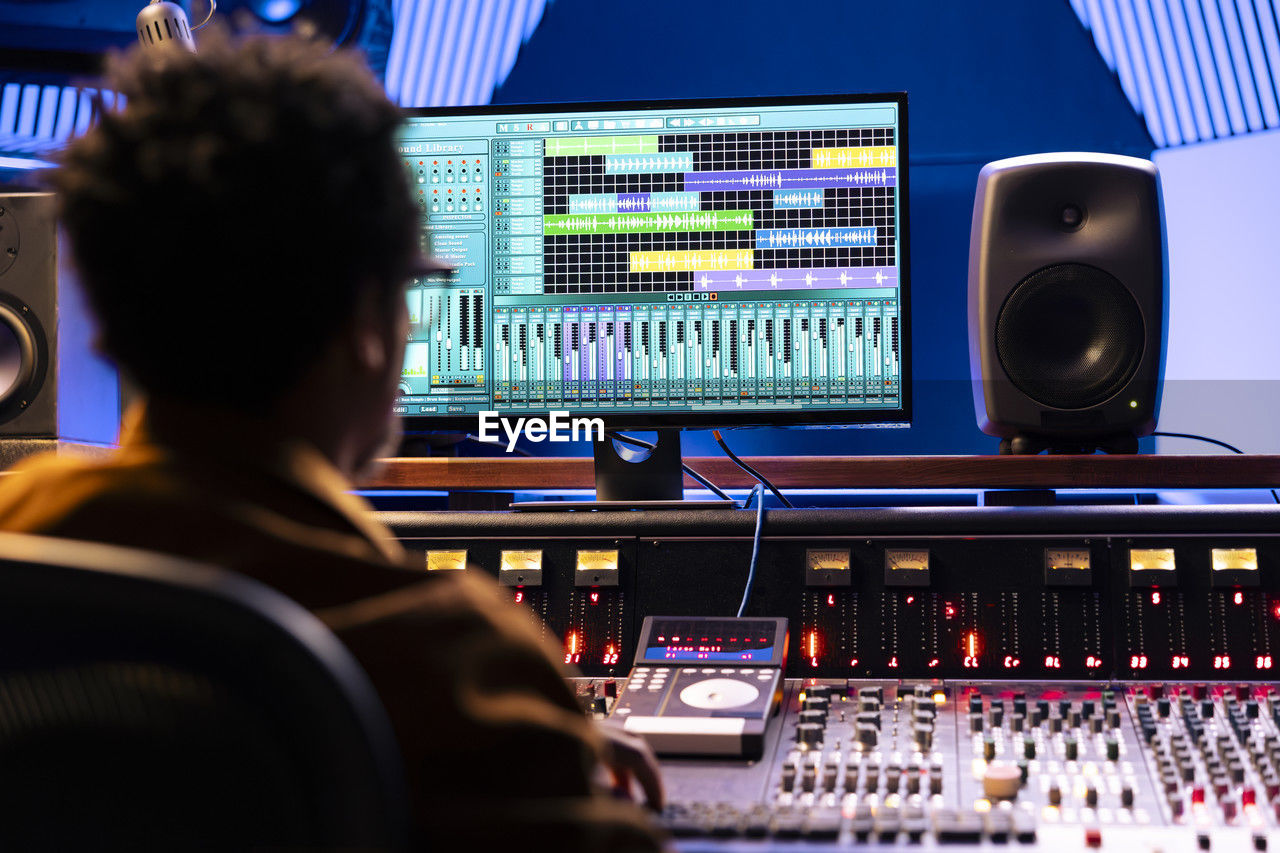 rear view of woman using sound mixer at home