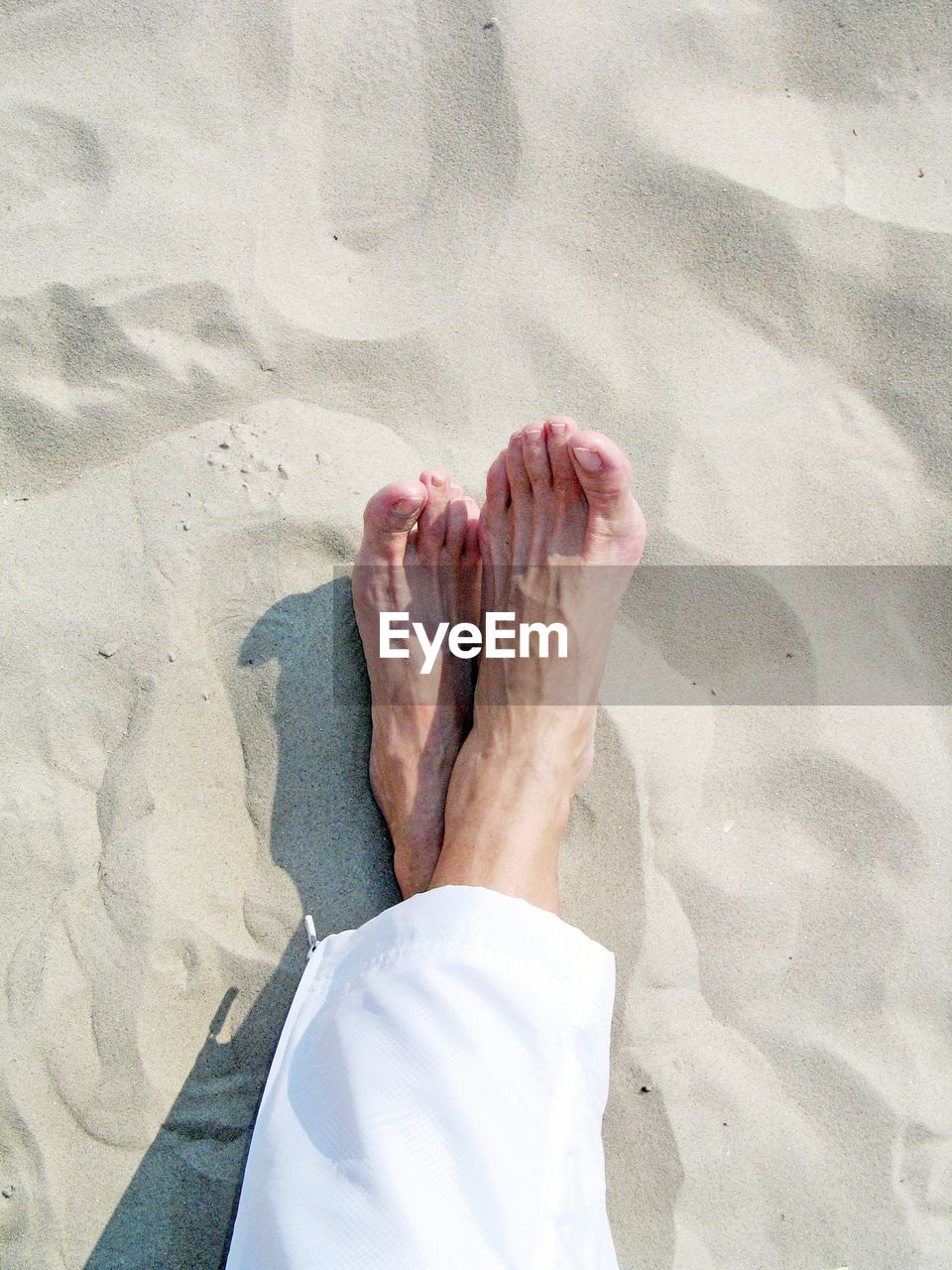 Low section of woman relaxing on sand