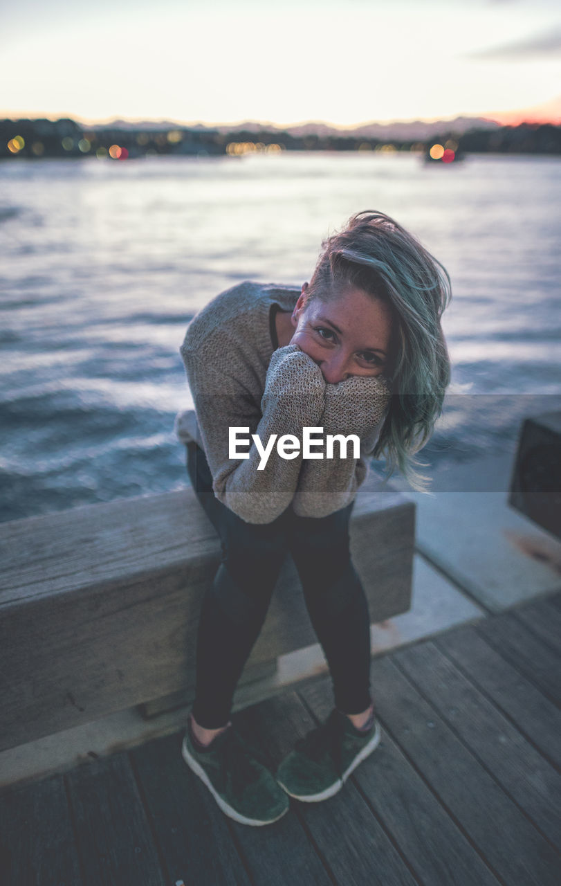 PORTRAIT OF YOUNG WOMAN ON PIER AGAINST SEA