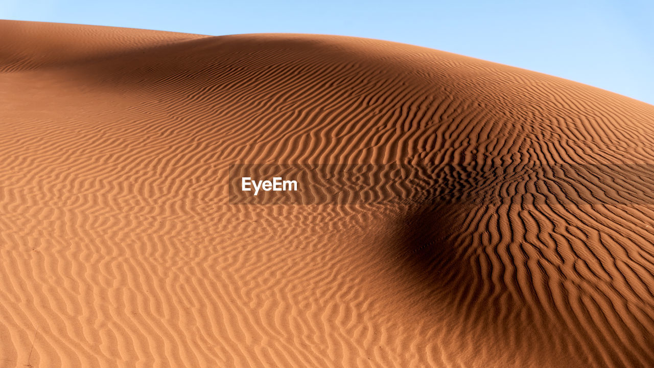 SCENIC VIEW OF SAND DUNE AGAINST CLEAR SKY