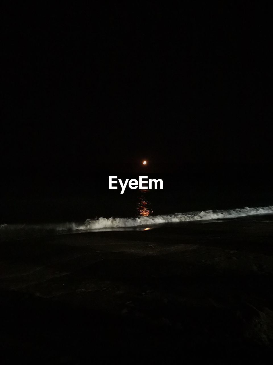 VIEW OF ILLUMINATED BEACH AGAINST SKY AT NIGHT