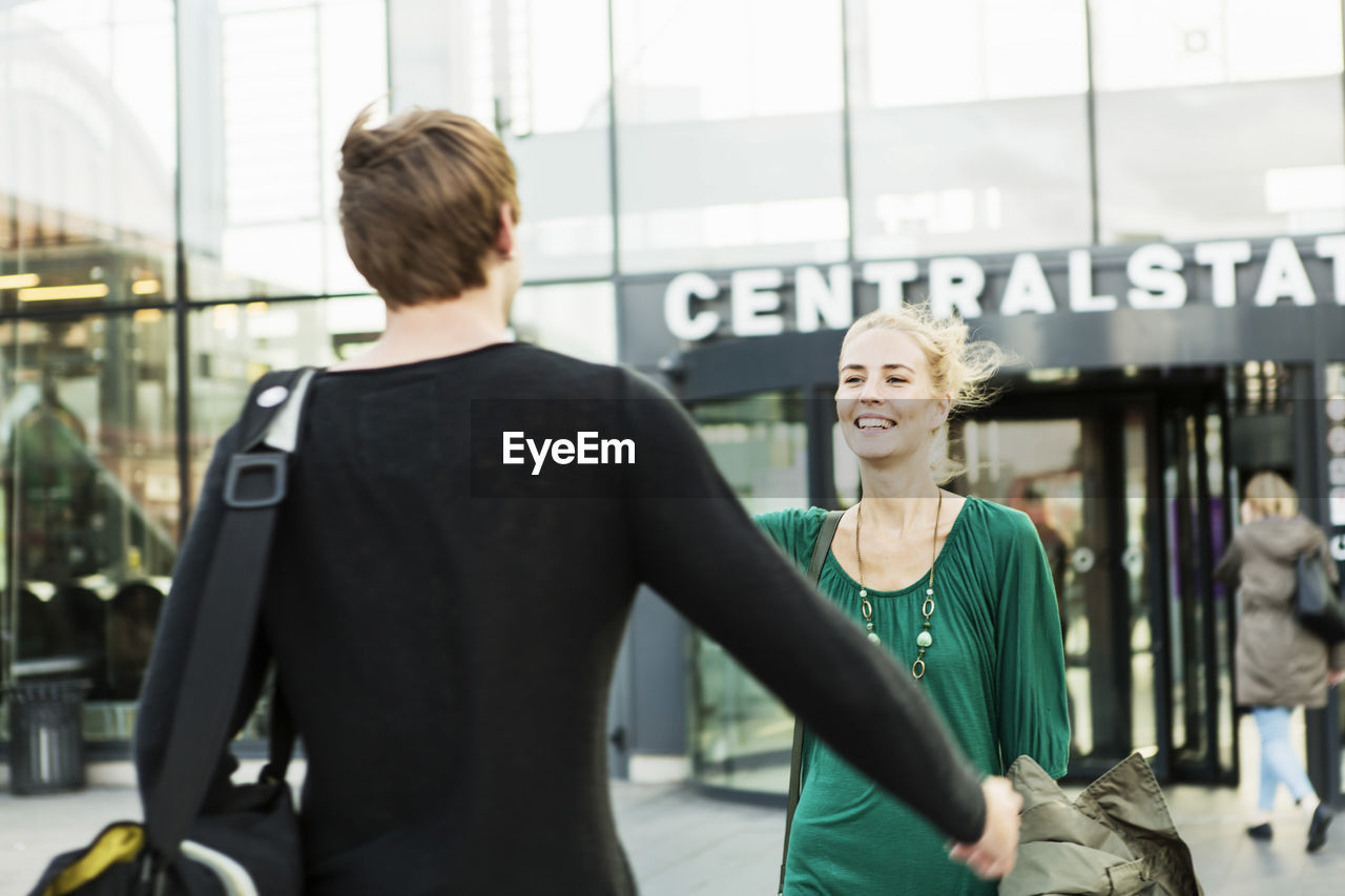 Friends greeting outside railroad station