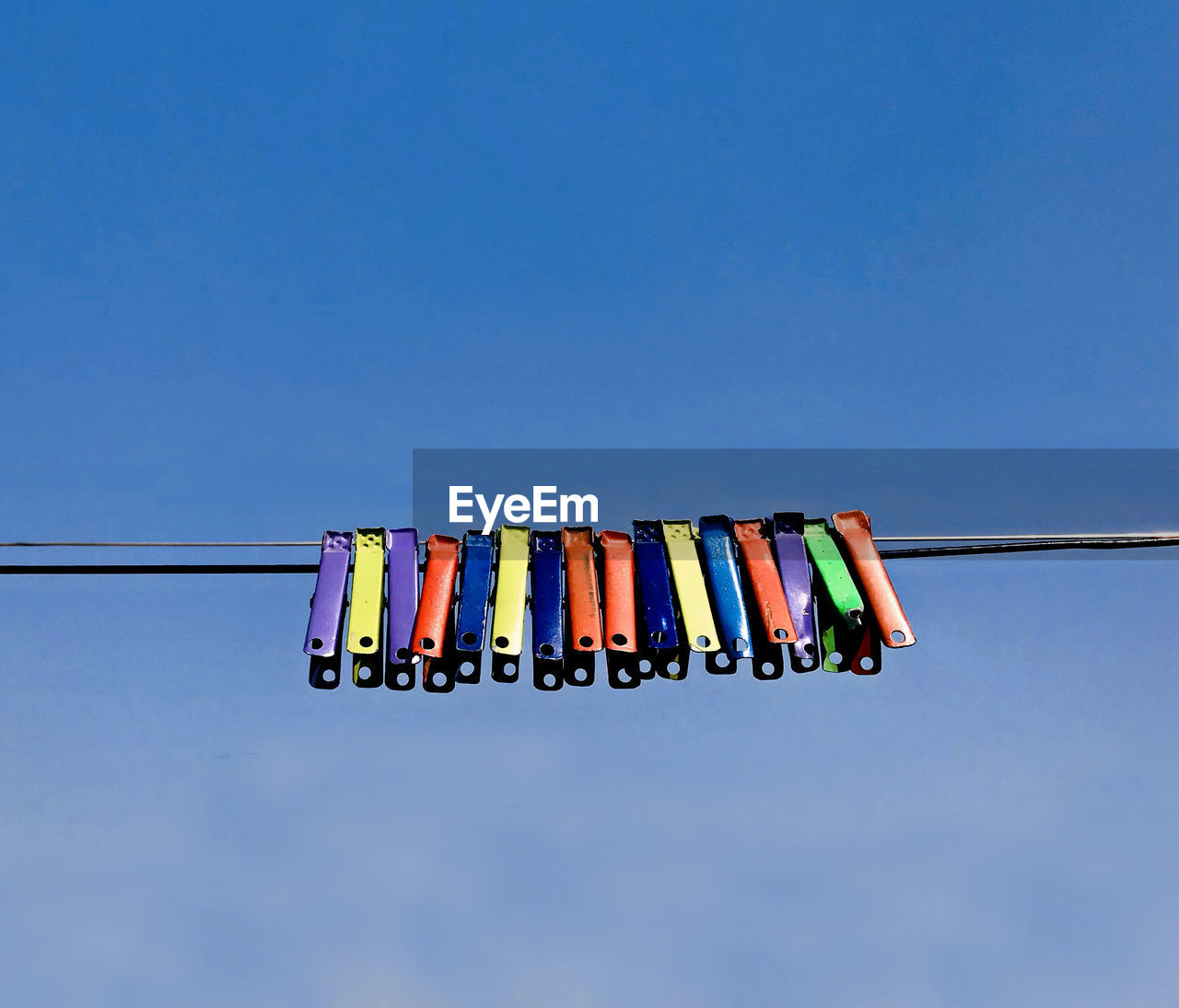 Low angle view of cloth clips against blue sky