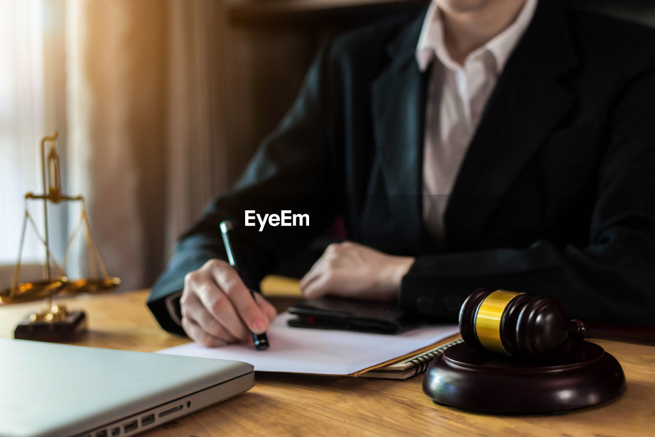 Midsection of lawyer sitting at table