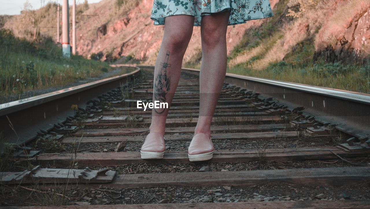 Low section of woman standing on railroad track