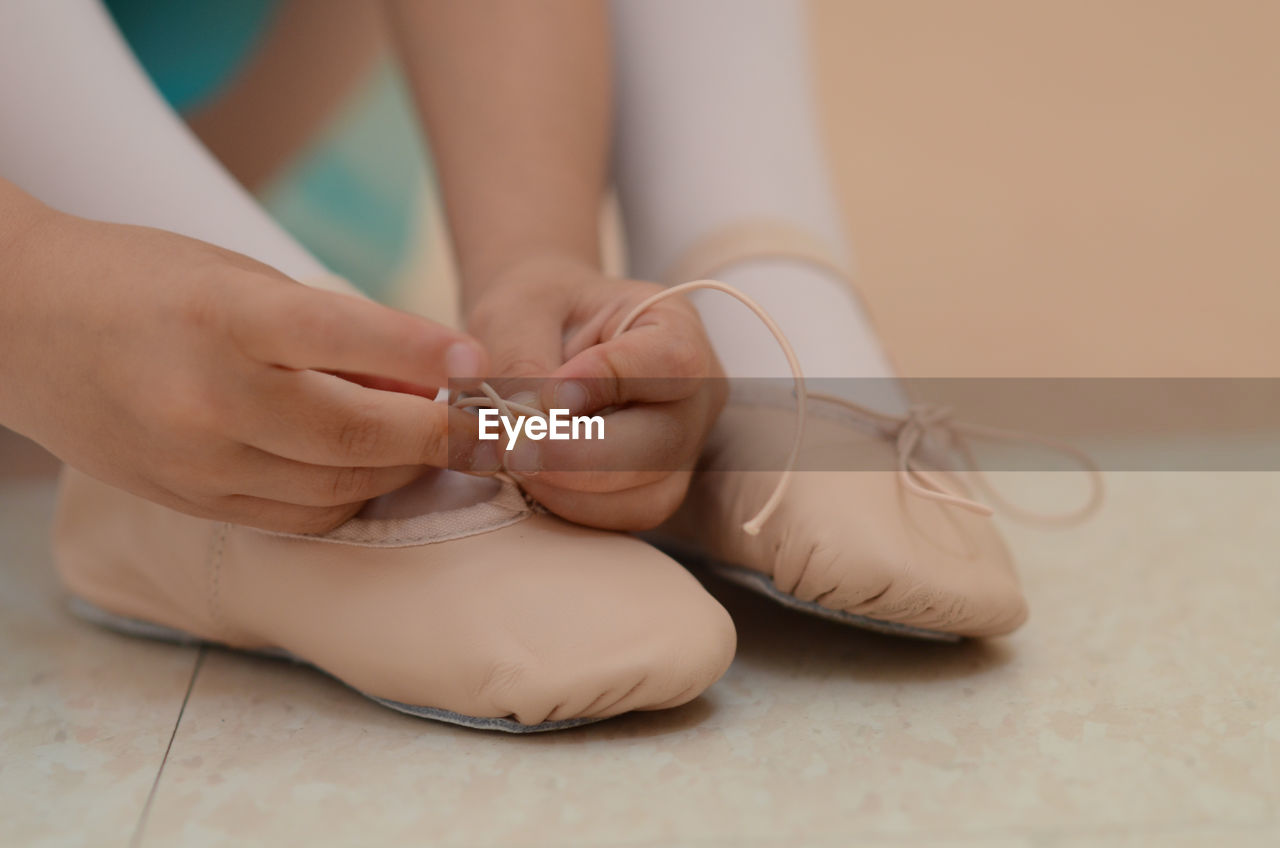 Cropped image of girl tying ballet shoe