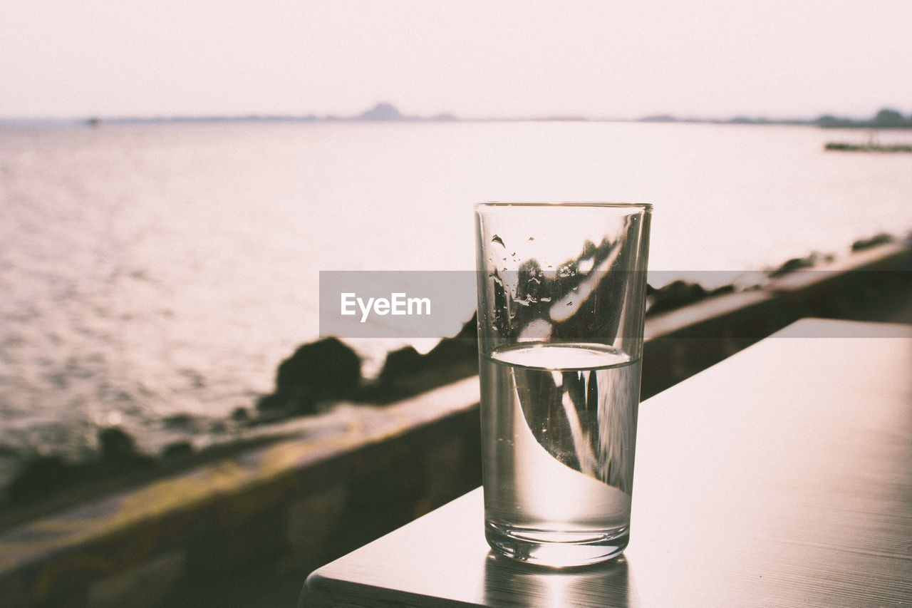 Glass of water on table against sea at pomorie