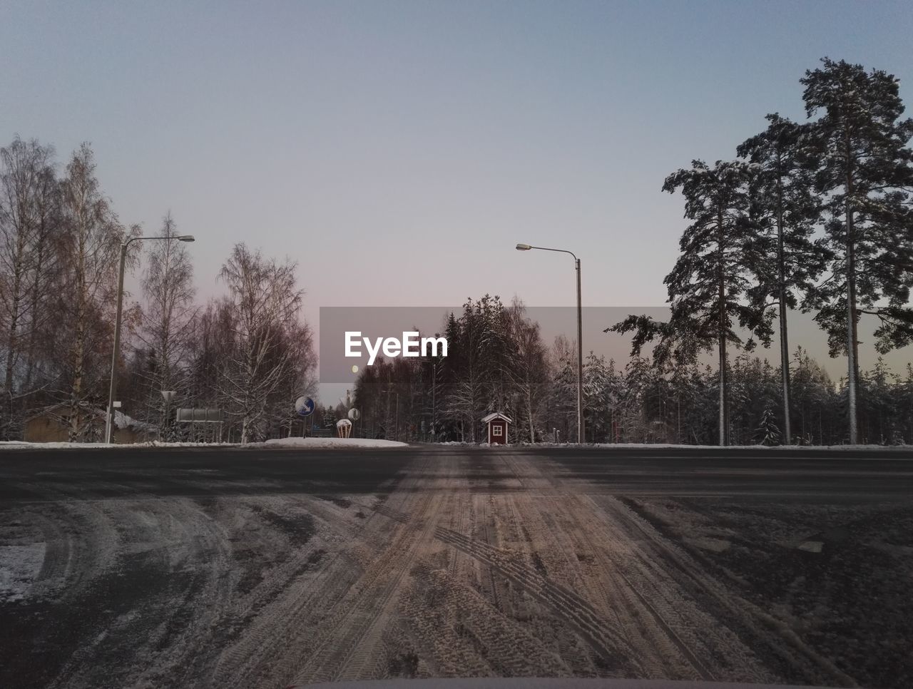 Road by trees against clear sky