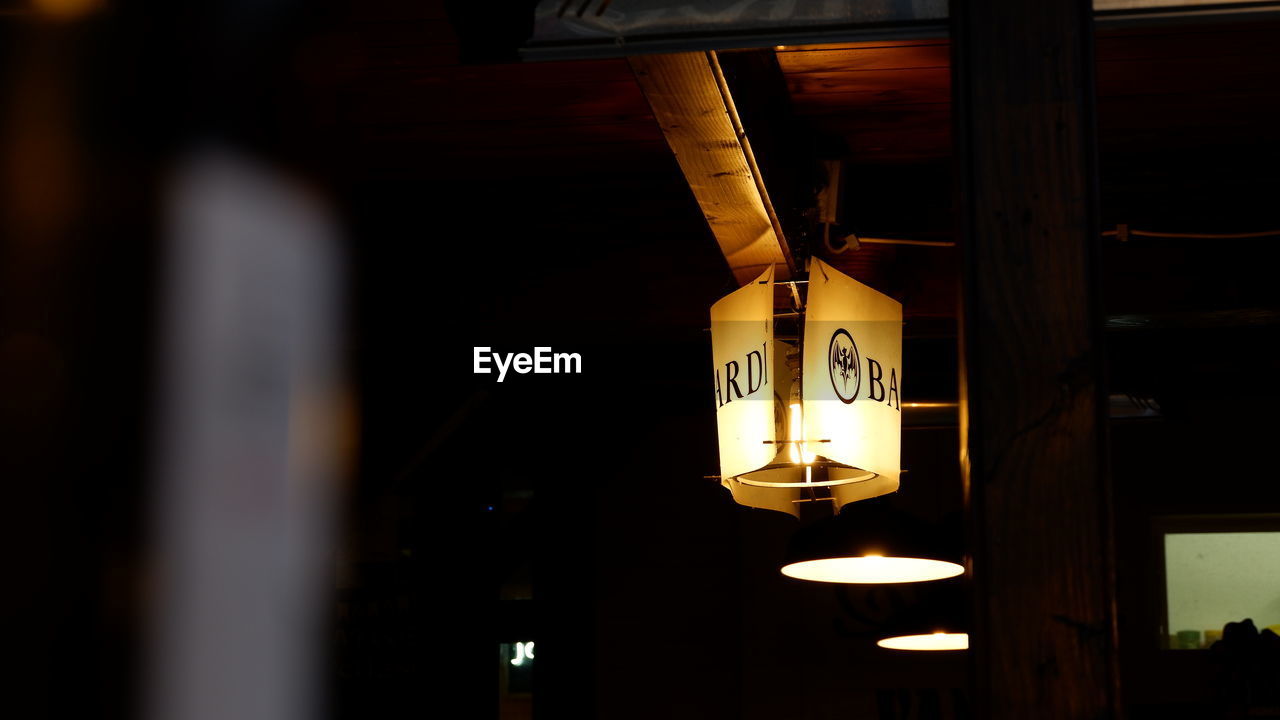 LOW ANGLE VIEW OF ILLUMINATED PENDANT LIGHT IN BUILDING