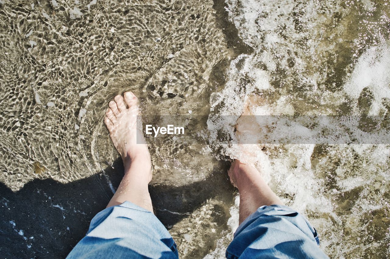 Low section of person in sea during sunny day