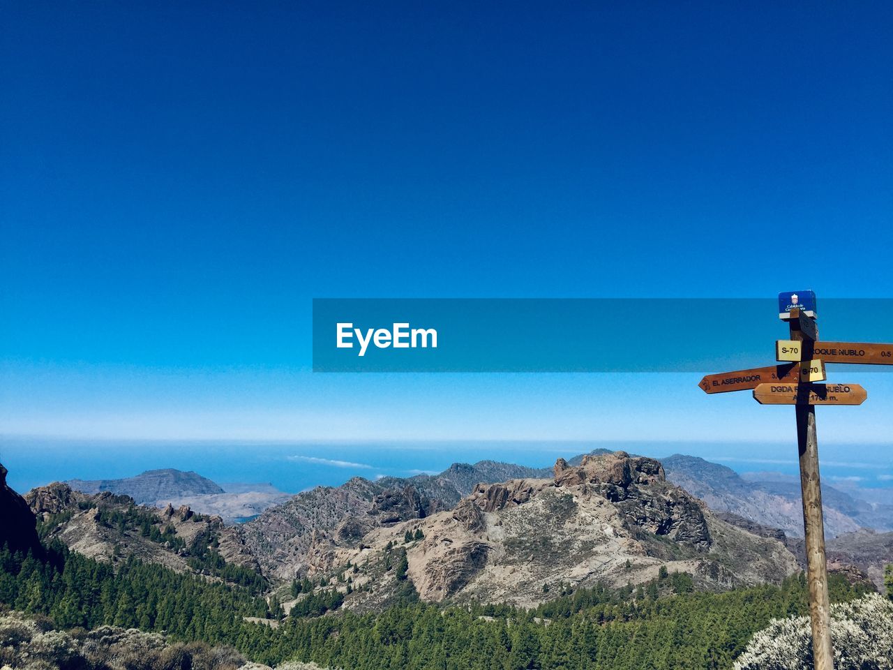 View of cross on mountain against blue sky