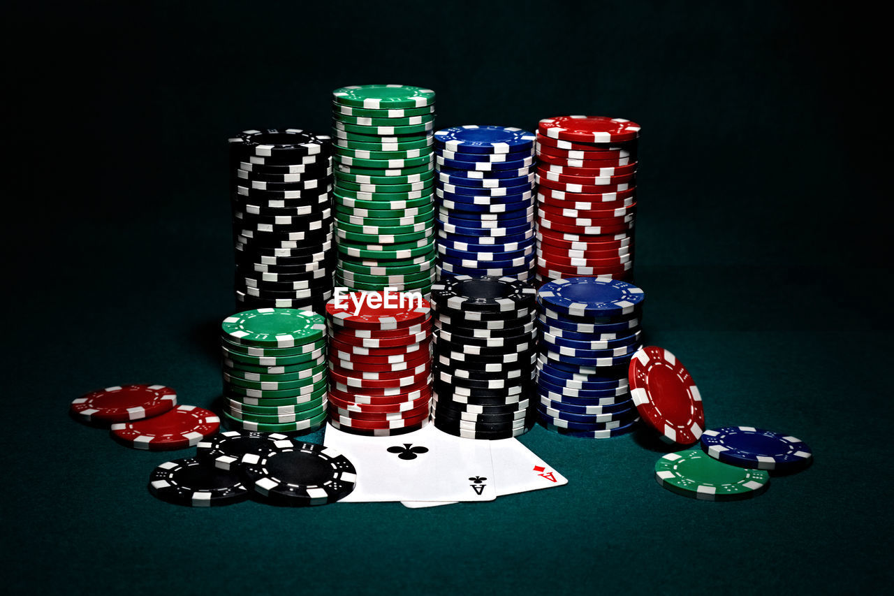 Stack of multi colored gambling chips on table against black background