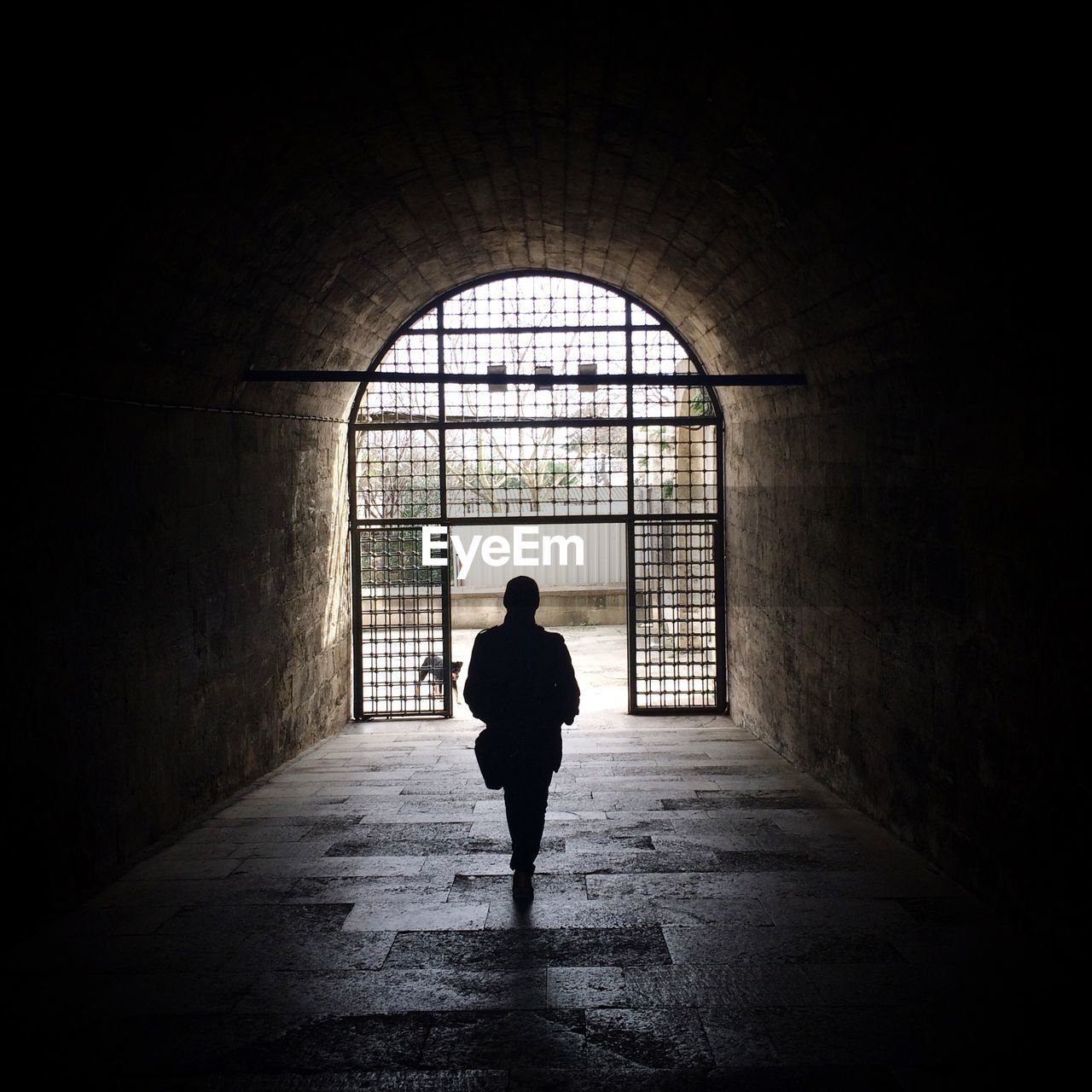 Rear view of person walking in tunnel