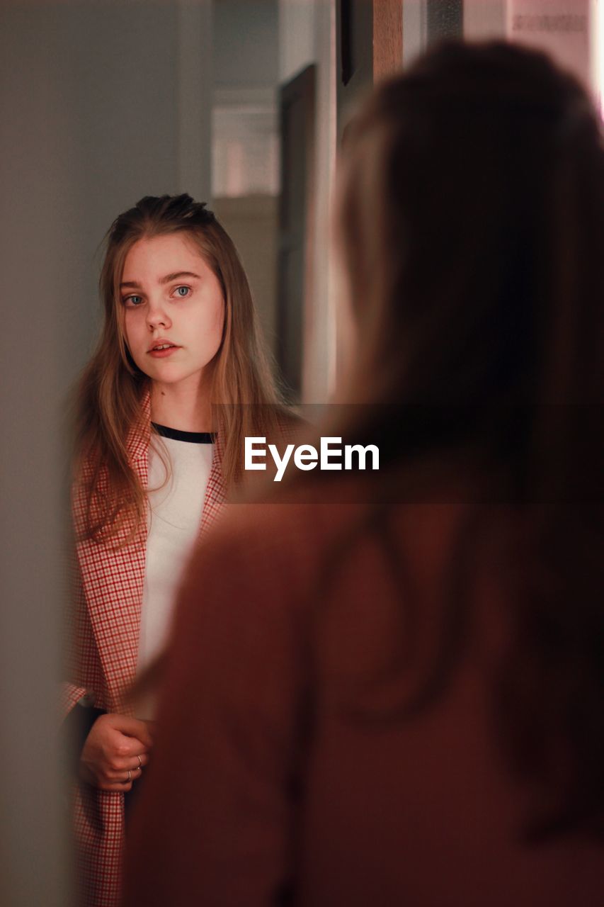 Portrait of woman standing in front of mirror