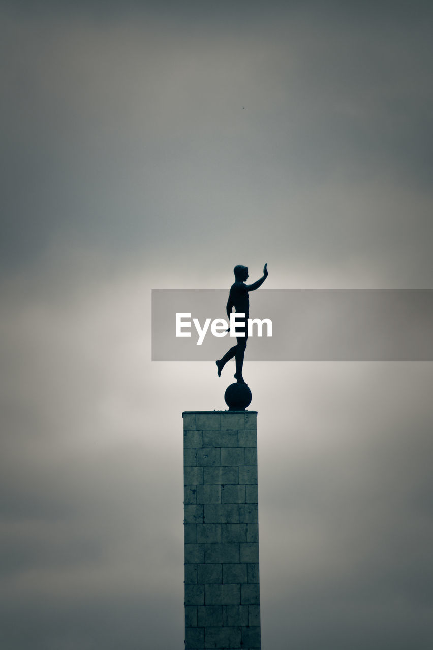 Low angle view of male statue against cloudy sky