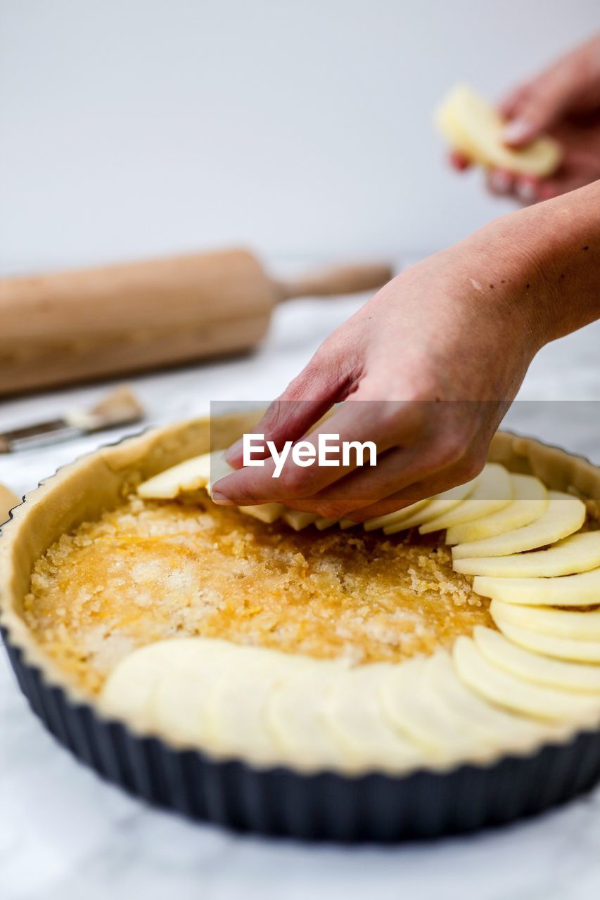 Close-up of person preparing apple pie