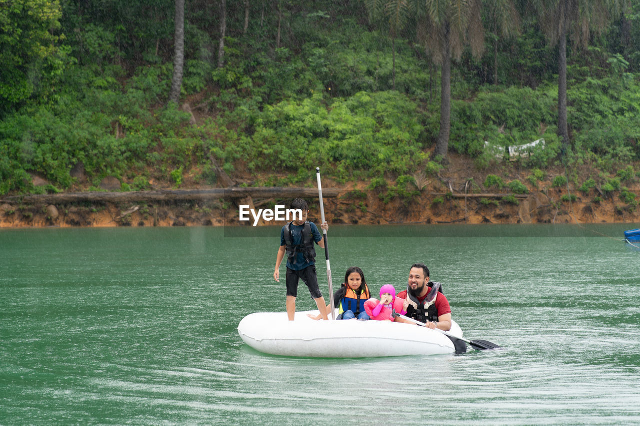 Man with children floating on inflatable ring over lake