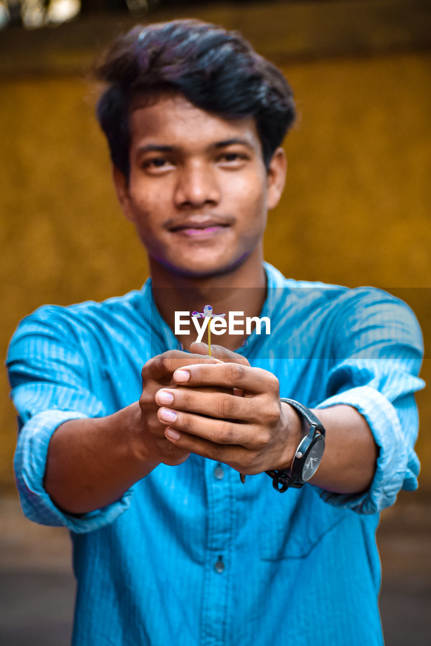 Portrait of young man holding flower