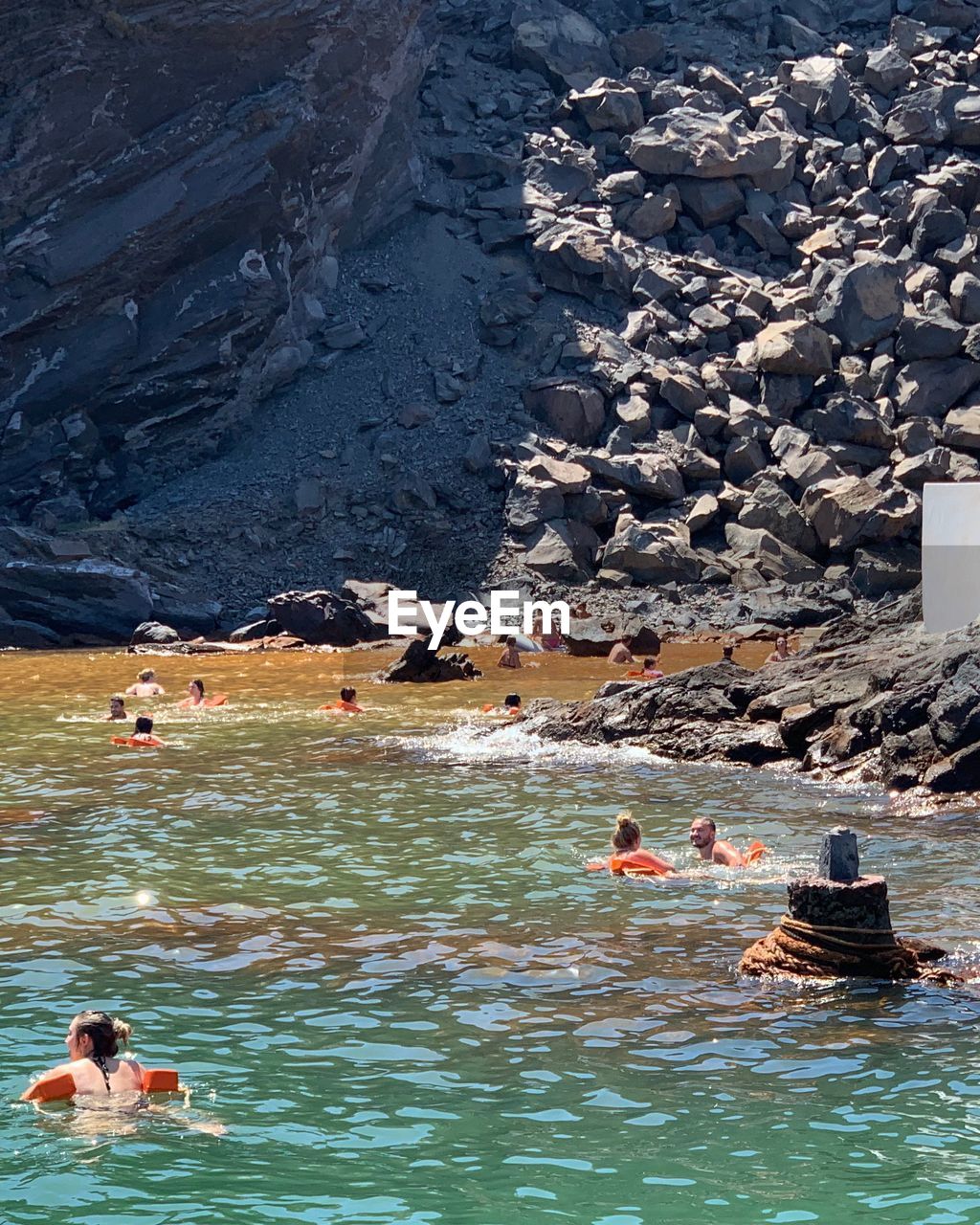 HIGH ANGLE VIEW OF PEOPLE ON ROCKS AT SEA