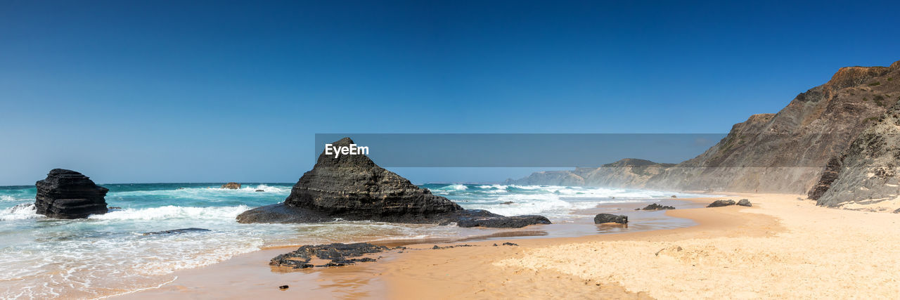 Panoramic view of beach against clear blue sky