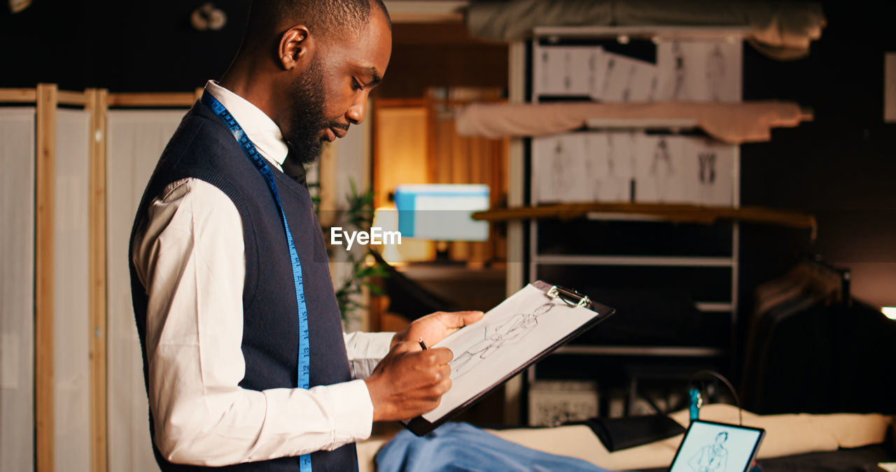 midsection of man reading book while standing in office