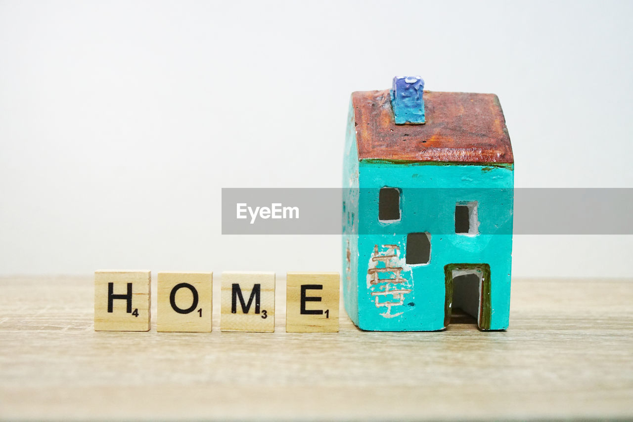 Close-up of model home with text on wooden blocks against white background