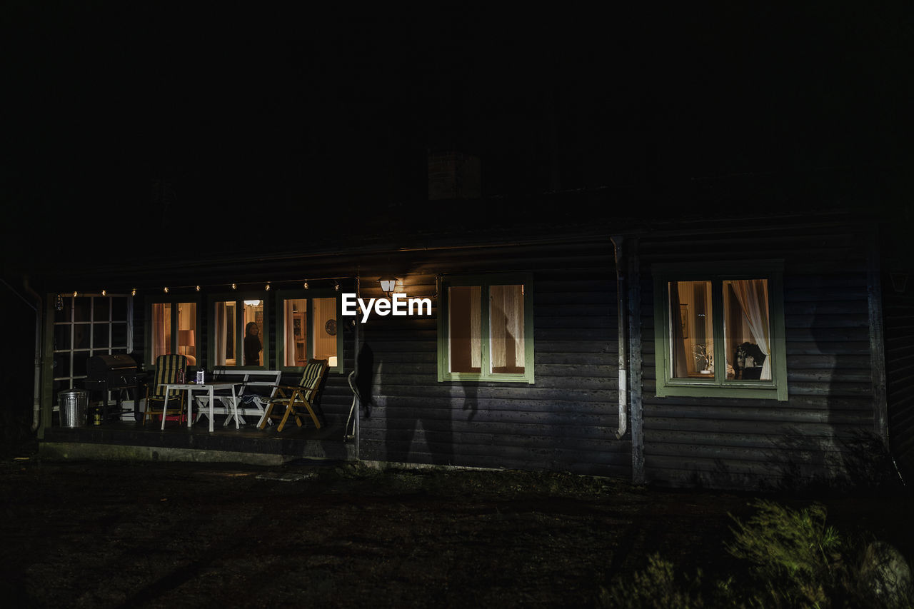 Shadow of demon on illuminated cabin at night