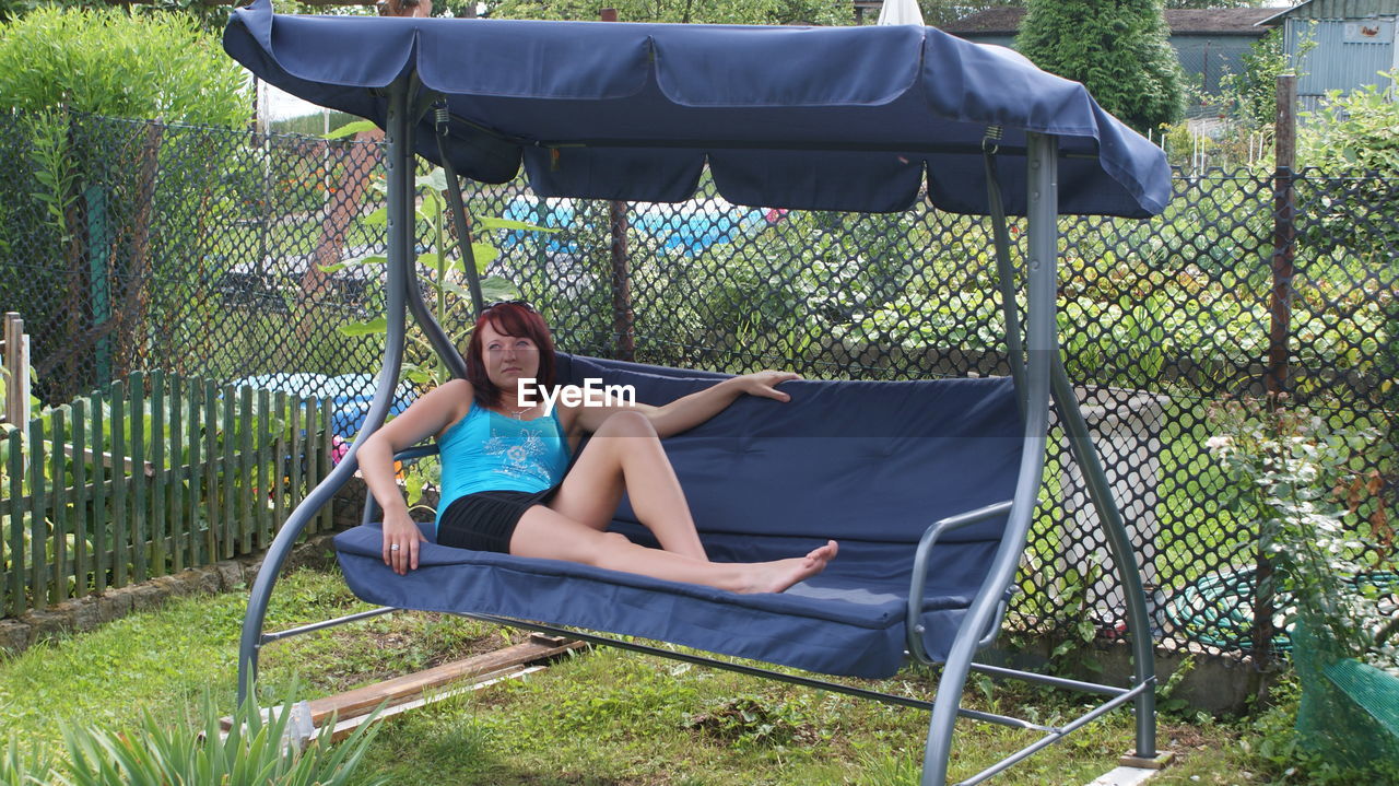 Young woman relaxing on swing in yard