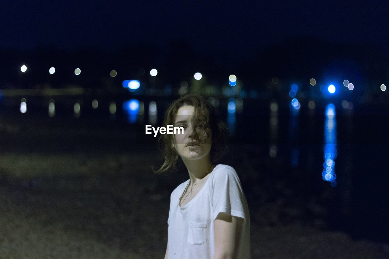 Portrait of girl standing at beach during night